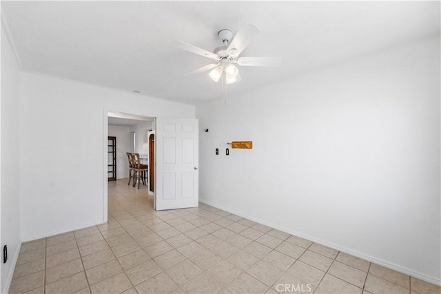 spare room with baseboards, ceiling fan, and light tile patterned floors
