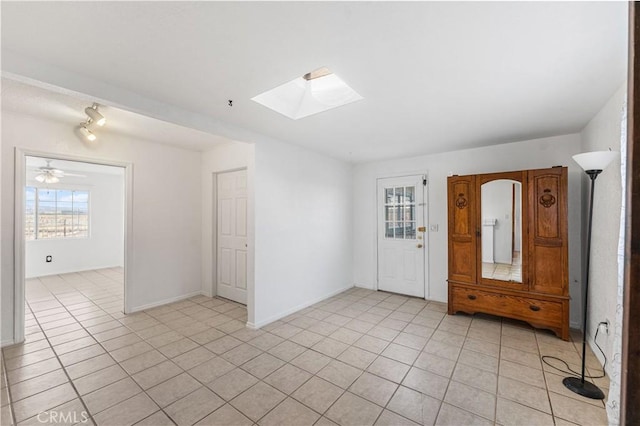 spare room featuring baseboards, a skylight, and light tile patterned floors