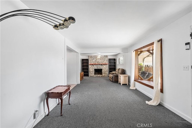 living area featuring baseboards, carpet, and a stone fireplace