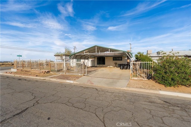 view of front of house featuring concrete driveway, fence private yard, a gate, and a detached carport
