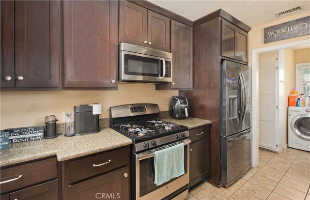 15709 Devonshire St, Granada Hills, CA 91344 - kitchen featuring appliances with stainless steel finishes, washer / dryer, light tile patterned flooring, dark brown cabinetry, and light countertops