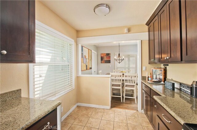 15709 Devonshire St, Granada Hills, CA 91344 - kitchen featuring a chandelier, dark brown cabinetry, light tile patterned floors, light stone countertops, and baseboards