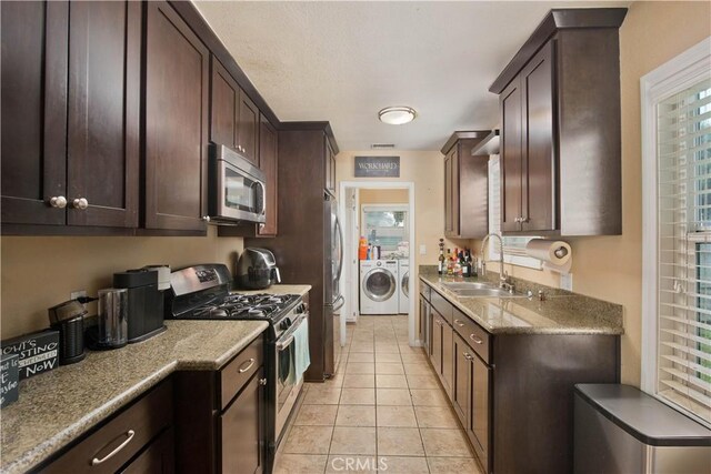 15709 Devonshire St, Granada Hills, CA 91344 - kitchen featuring appliances with stainless steel finishes, washing machine and dryer, a sink, dark brown cabinets, and light tile patterned floors