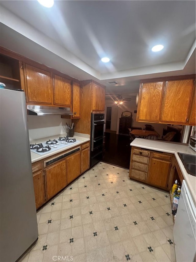 5945 Crystal Hill St, Riverside, CA 92504 - kitchen with white appliances, brown cabinetry, under cabinet range hood, a raised ceiling, and a sink