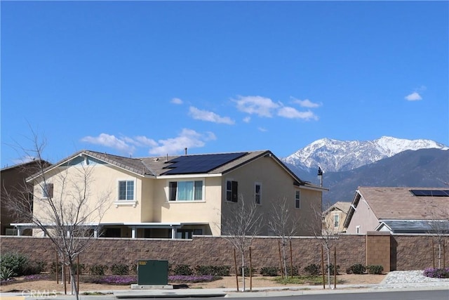 5597 Royal Oaks Way, Fontana, CA 92336 - back of house featuring stucco siding, a mountain view, and solar panels