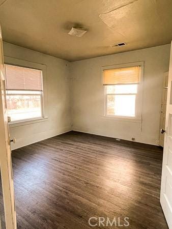 spare room featuring plenty of natural light, dark wood-style floors, and visible vents