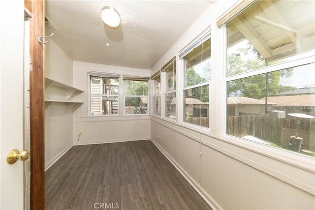 unfurnished sunroom featuring baseboards and wood finished floors