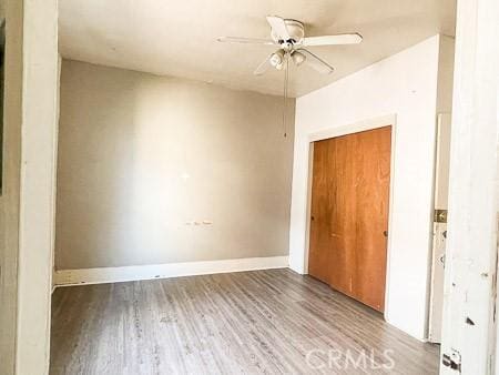 unfurnished room featuring a ceiling fan, baseboards, and wood finished floors