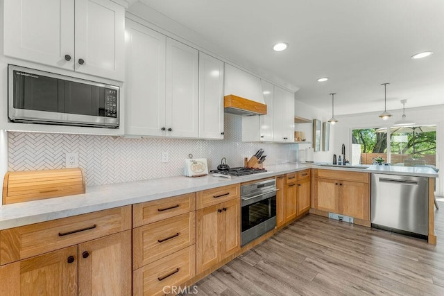 kitchen with a peninsula, a sink, appliances with stainless steel finishes, and decorative backsplash