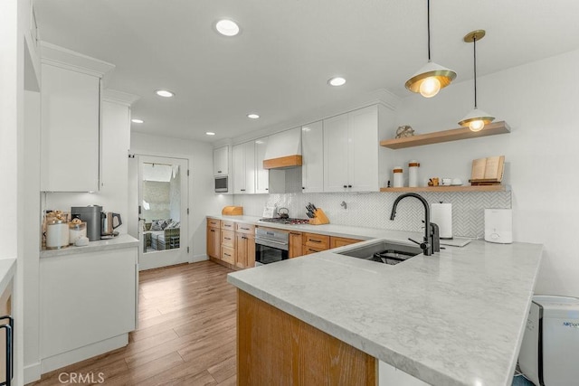 kitchen featuring appliances with stainless steel finishes, tasteful backsplash, a sink, light countertops, and a peninsula