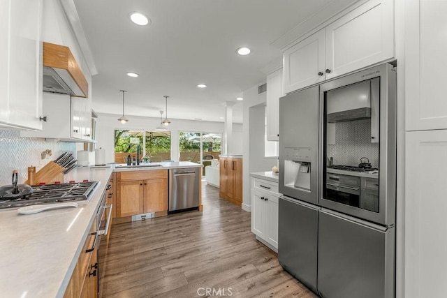 kitchen featuring white cabinets, appliances with stainless steel finishes, light countertops, a peninsula, and decorative backsplash