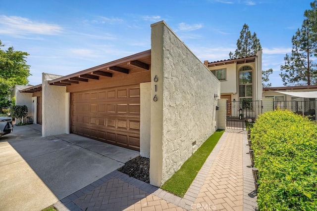view of property exterior with fence, a gate, and stucco siding