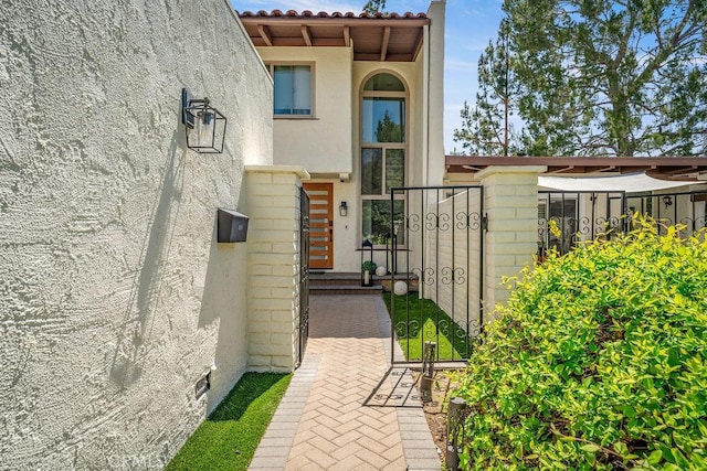 view of exterior entry with a tile roof and stucco siding