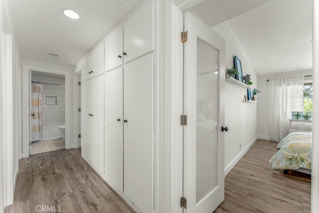 hall featuring light wood-type flooring and baseboards