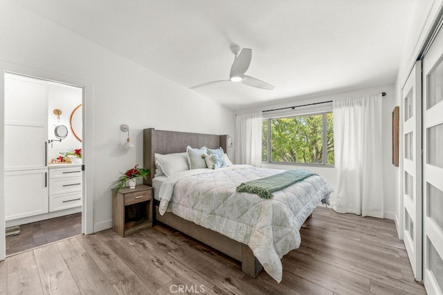 bedroom featuring a ceiling fan, wood finished floors, and ensuite bathroom