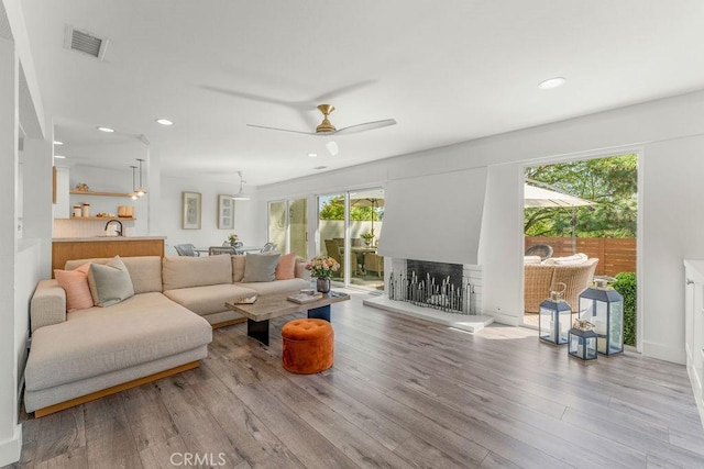 living room featuring a ceiling fan, visible vents, wood finished floors, and recessed lighting