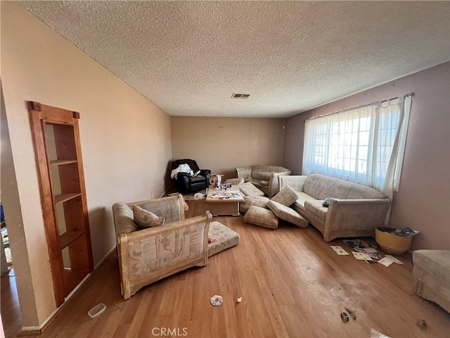 living area featuring wood finished floors, a textured ceiling, and visible vents