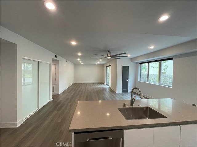 kitchen with a ceiling fan, stainless steel dishwasher, a sink, baseboards, and open floor plan