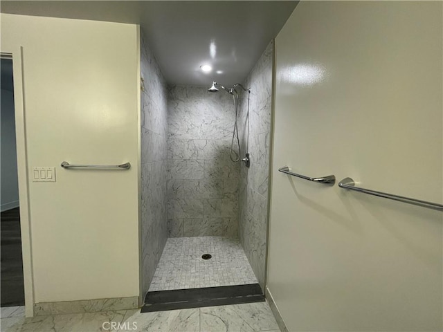 bathroom with baseboards, a tile shower, and marble finish floor