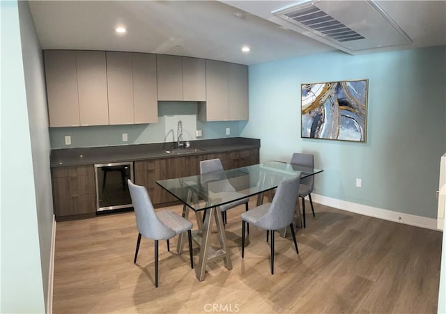 kitchen featuring dark countertops, a sink, light wood finished floors, and dishwasher