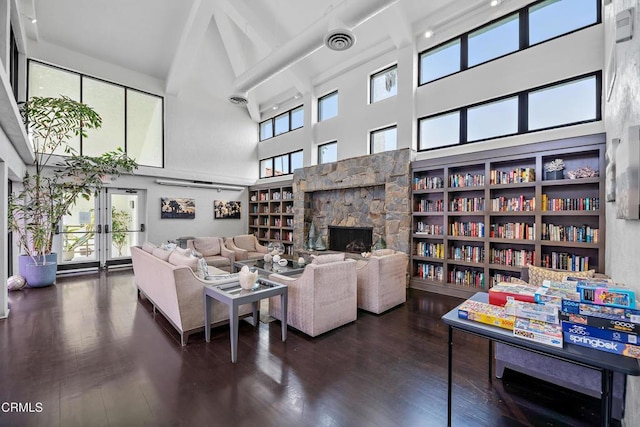 living room featuring a high ceiling, visible vents, wood finished floors, and a fireplace