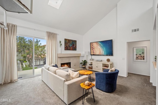 living area with visible vents, a premium fireplace, high vaulted ceiling, carpet flooring, and a skylight