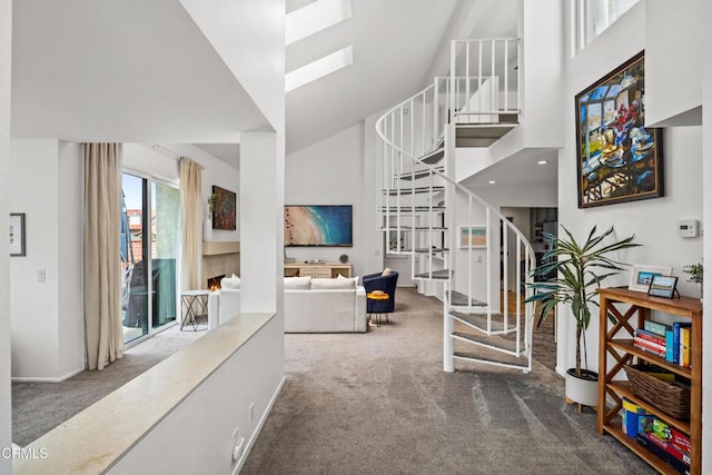 interior space with carpet flooring, a towering ceiling, a skylight, and stairway