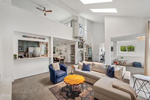 carpeted living room featuring a skylight, a high ceiling, and stairs
