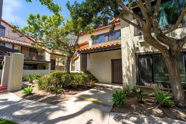 view of front of home with a tiled roof, stairs, and stucco siding