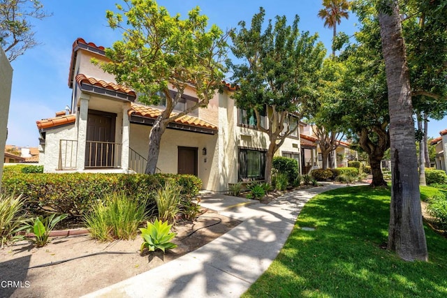 mediterranean / spanish-style house featuring stucco siding, a tiled roof, and a front yard