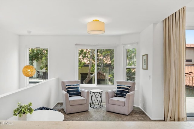 living area featuring carpet floors, baseboards, and a healthy amount of sunlight
