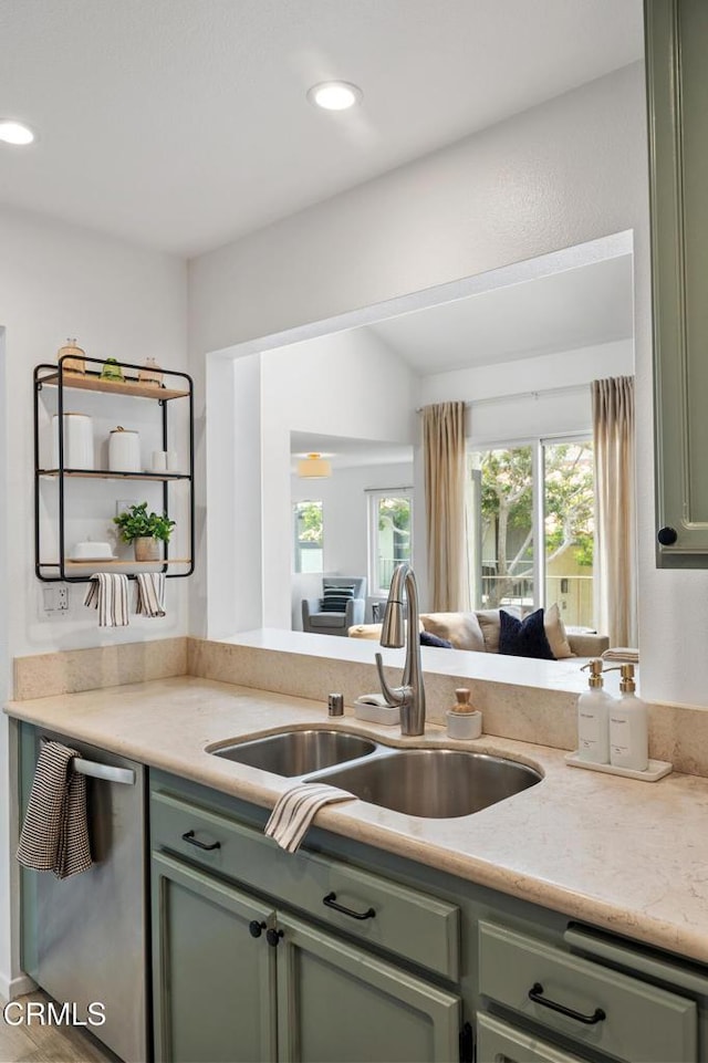 kitchen with stainless steel dishwasher, a sink, and green cabinets