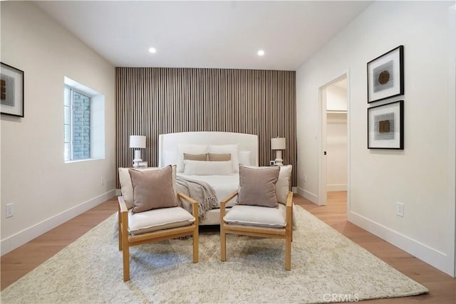 bedroom featuring a walk in closet, baseboards, recessed lighting, and wood finished floors