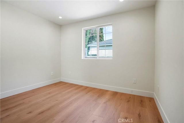 spare room featuring recessed lighting, baseboards, and light wood-type flooring