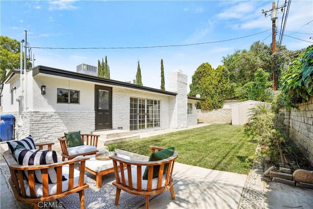 back of house with brick siding, stucco siding, a chimney, a patio area, and a lawn