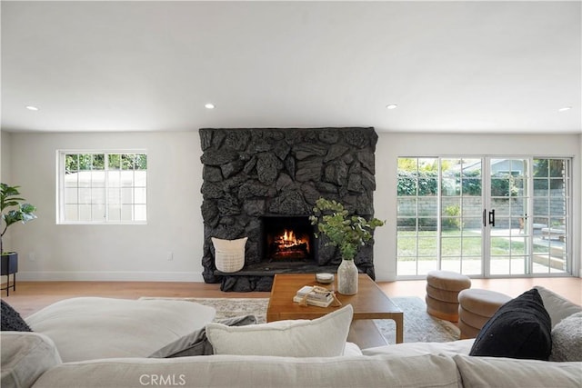 living area featuring a fireplace, baseboards, a wealth of natural light, and light wood-style floors