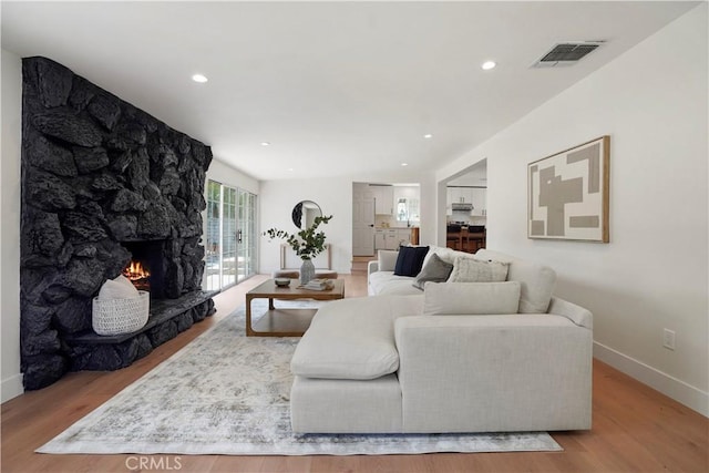 living area with baseboards, visible vents, wood finished floors, and a fireplace