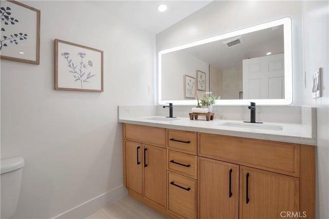 full bathroom featuring double vanity, toilet, visible vents, and a sink