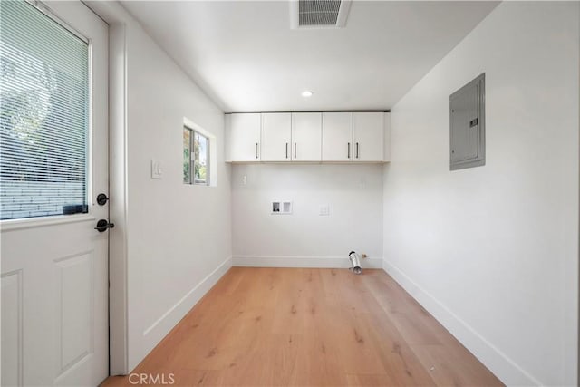 laundry area featuring electric panel, visible vents, cabinet space, baseboards, and light wood-style flooring