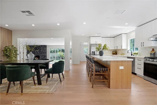 kitchen with a breakfast bar area, visible vents, appliances with stainless steel finishes, a center island, and light wood-style floors