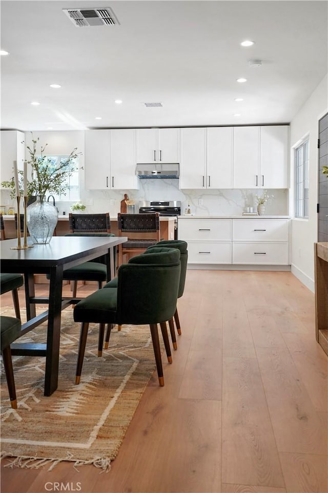 kitchen with white cabinets, under cabinet range hood, electric range, and visible vents