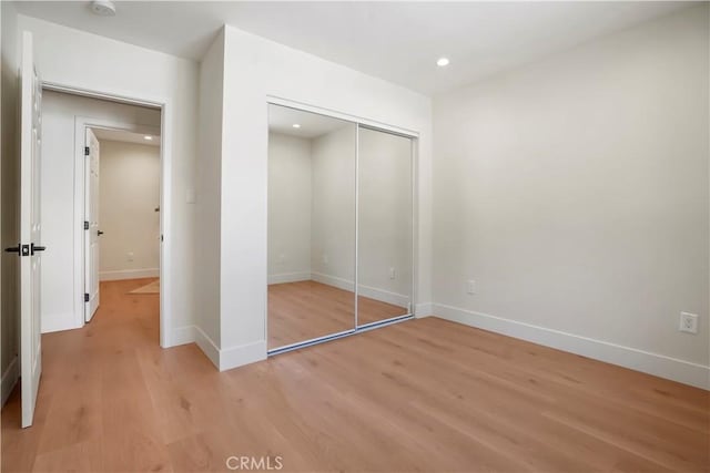 unfurnished bedroom with recessed lighting, baseboards, light wood finished floors, and a closet