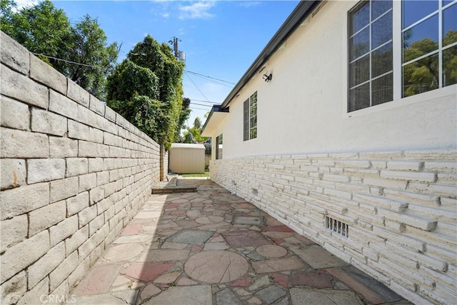 view of side of home featuring a patio, a fenced backyard, and stucco siding