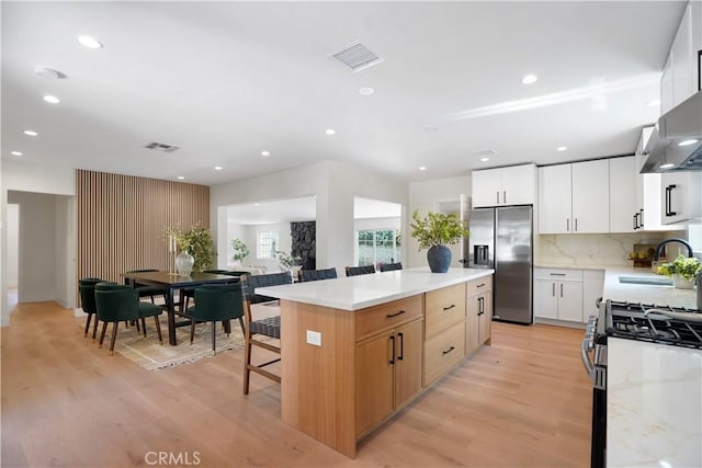 kitchen featuring a sink, light wood finished floors, stainless steel appliances, a kitchen island, and visible vents