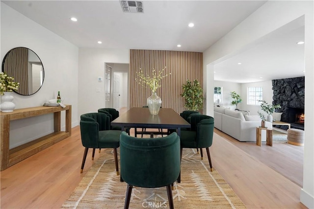 dining space featuring visible vents, baseboards, a stone fireplace, light wood-type flooring, and recessed lighting