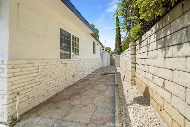view of home's exterior featuring fence, a patio, stucco siding, and brick siding