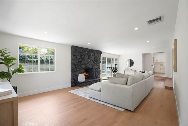 living area with a healthy amount of sunlight, baseboards, light wood-style flooring, and visible vents