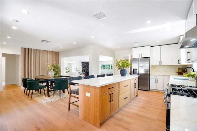 18324 Sylvan St, Tarzana, CA 91335 - kitchen with stainless steel appliances, a sink, a kitchen island, light wood finished floors, and light countertops