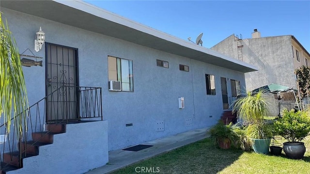 view of property exterior featuring a yard, crawl space, cooling unit, and stucco siding