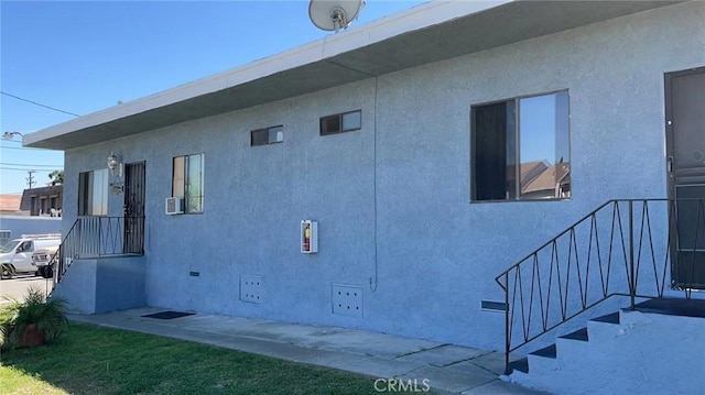 view of side of home with crawl space and stucco siding